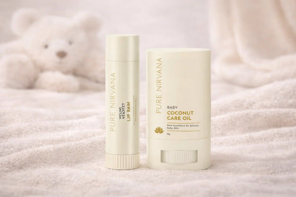 Baby coconut care oil and velvet lip balm skincare products on soft fabric with a plush bear background